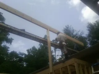 Carpenter setting a ridge beam over a new addition frame — Ice Dam Removal by Roofing Brothers in Aydlett