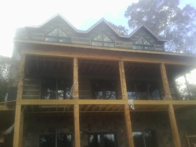 Dormers and porch framing on a large log home under construction — Roof Coating work by our crew in Aydlett