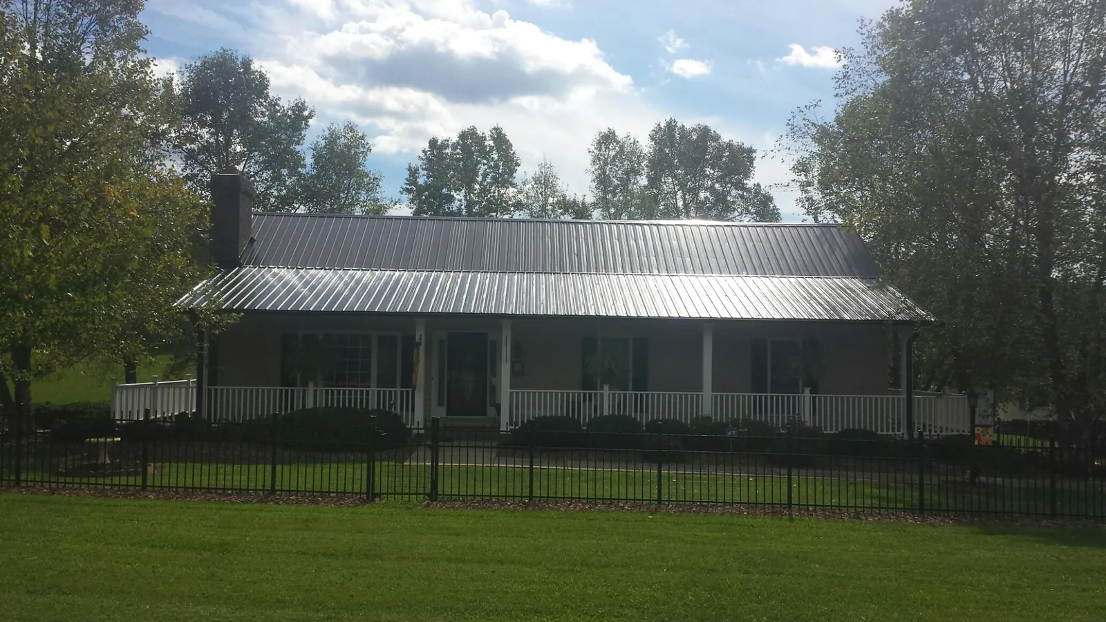 Gray metal roof on a brick ranch with a full width front porch — Gutter Guard Installation work by our crew in Aydlett