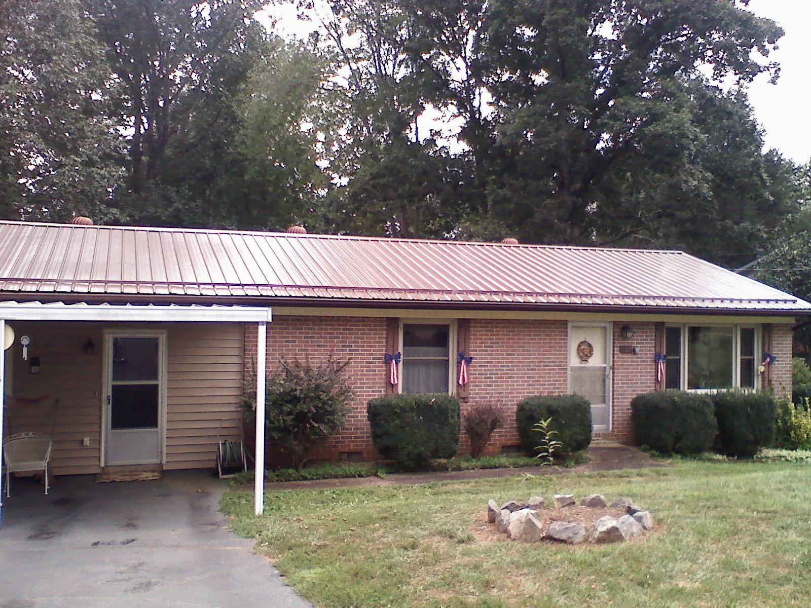 Bronze metal roof and carport on a brick ranch home — Roof Repair work by our crew in Aydlett